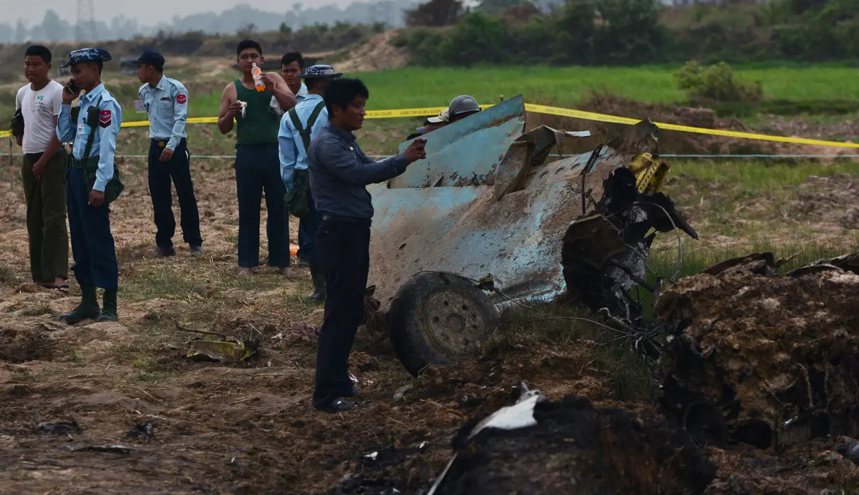 Tentara Myanmar menjaga reruntuhan jet tempur yang jatuh di area persawahan desa Kyunkone, berjarak satu jam dari ibu kota Naypyidaw, Selasa (3/4). Pihak kepolisian mengatakan pesawat yang jatuh merupakan tipe F-7 dengan kemudi tunggal. (AFP Photo)