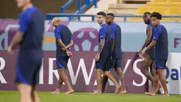 Kapten timnas AS Christian Pulisic (tengah) dan pemain lain berjalan tanpa alas kaki di lapangan selama sesi latihan resmi di Stadion Al-Gharafa SC, Doha, Senin (28/11/2022). Pertandingan AS vs Iran ini diprediksi akan berlangsung panas karena memperebutkan posisi 16 besar Piala Dunia 2022. (AP Photo/Ashley Landis)