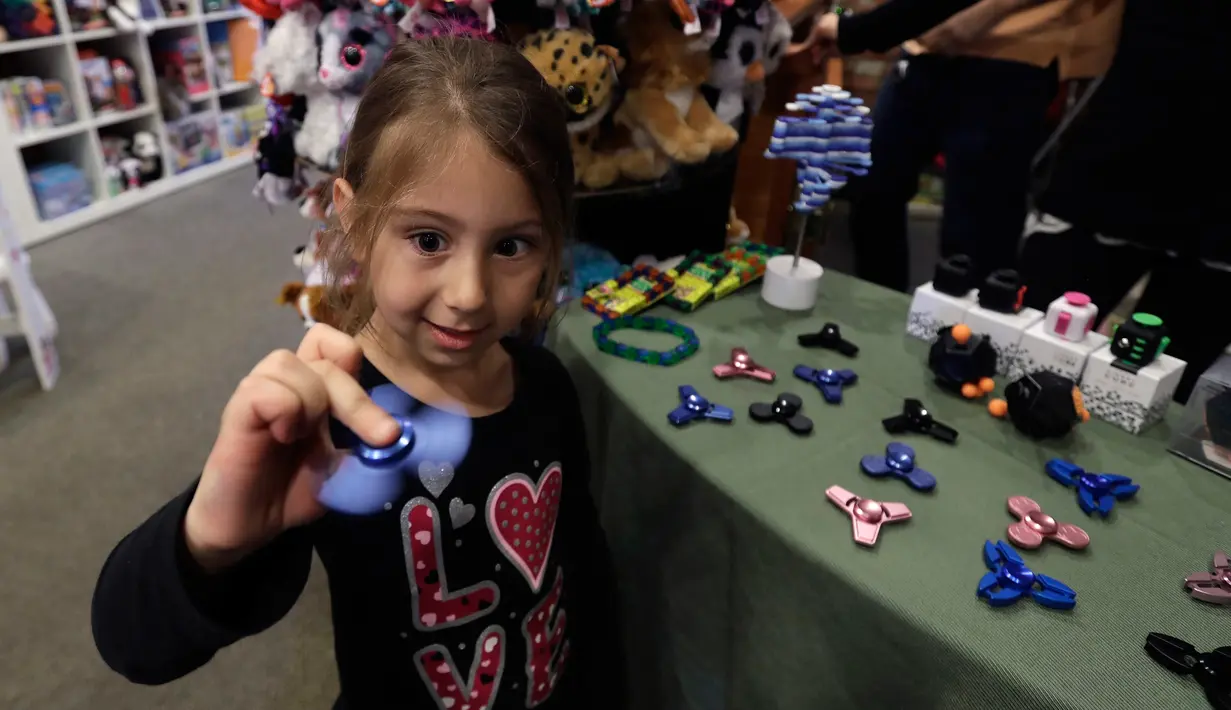 Seorang anak memainkan fidget spinner di sebuah yang bernama toko Funky Monkey Toys di Oxford, Mich (11/5). Cara memainkannya bisa memutarnya hanya dengan menggunakan jari, dan memegang bagian tengah fidget spinner.(AP Photo / Carlos Osorio)