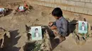 Seorang anak berdoa di makam anak-anak sekolah di sebuah pemakaman di provinsi kubu pemberontak Huthi di Saada (4/9). Anak-anak tersebut tewas terkena serangan udara koalisi pimpinan Saudi di pasar Dahyan pada bulan Agustus. (AFP Photo/Stringer)
