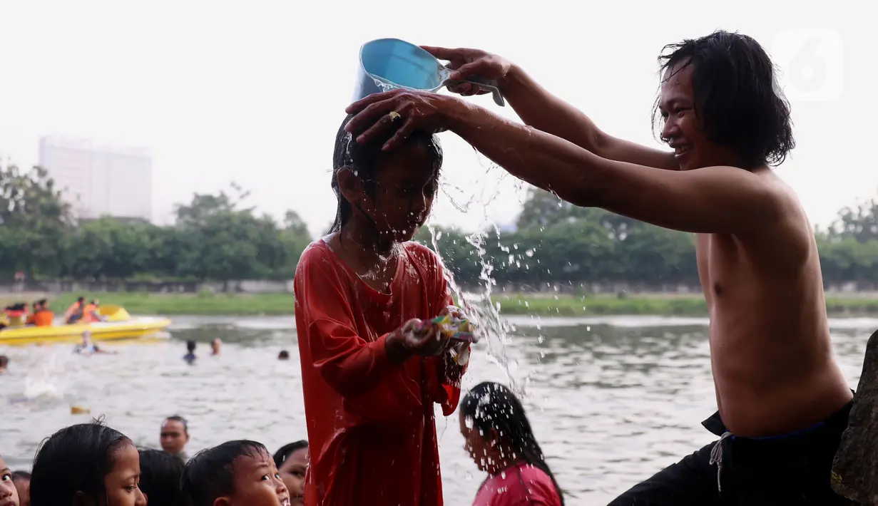 Seorang anak saat dikeramas di bantaran sungai Cisadane di kawasan Babakan, Kota Tangerang, Jumat (1/4/2022). Keramas bersama merupakan tradisi warga yang berada dikawasan tersebur sebagai simbol membersihkan diri untuk menyambut bulan Ramadhan. (Liputan6.com/Angga Yuniar)