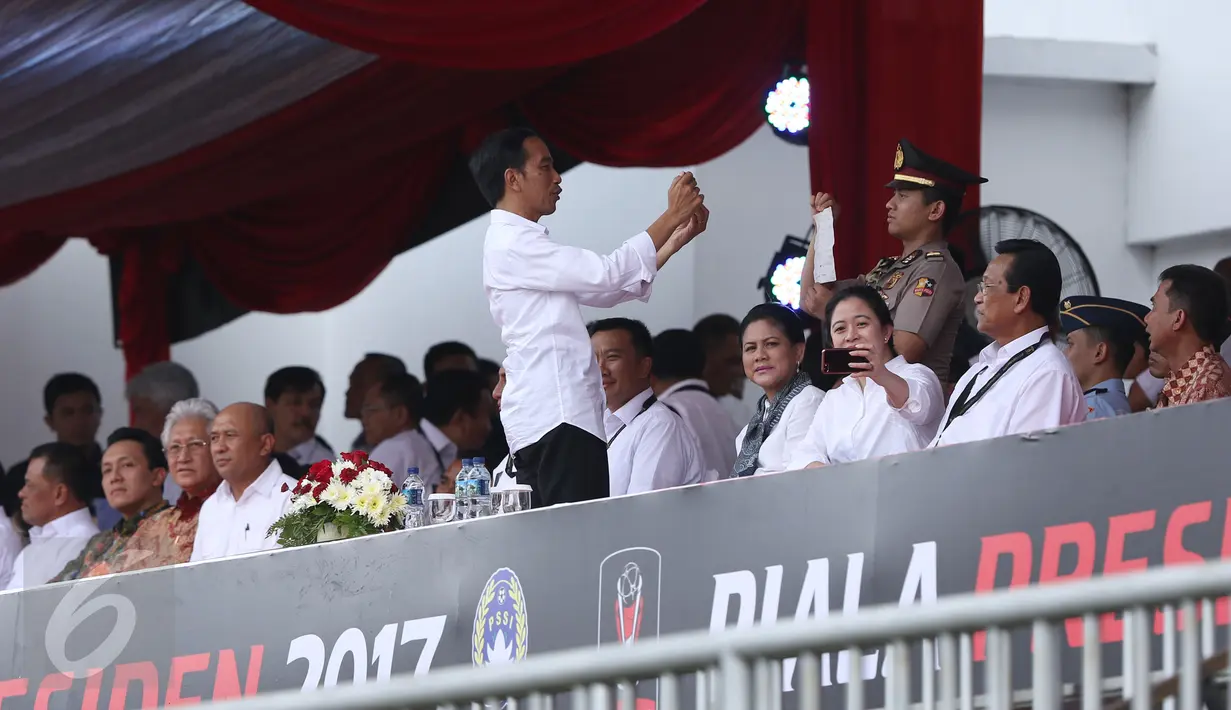 Presiden Joko Widodo (tengah) memotret saat menyaksikan laga PSS dan Persipura di turnamen Piala Presiden 2017 di Stadion Maguwoharjo, Sleman, Sabtu (4/2). 31.000 penonton menyaksikan laga pembuka Piala Presiden 2017. (Liputan6.com/Helmi Fithriansyah)