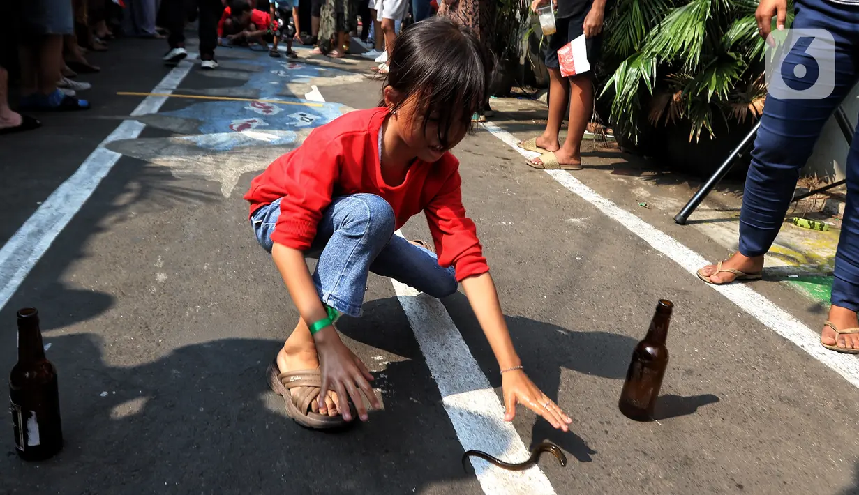 Seorang anak berusaha menangkap belut untuk dimasukkan ke dalam botol saat mengikuti lomba menyambut HUT ke-78 RI. (Liputan6.com/Angga Yuniar)