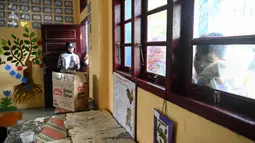 Seorang siswa melihat melalui jendela ketika teman-temannya menerima vaksin virus corona COVID-19 Sinovac di sebuah sekolah dasar di Darul Imarah, Kabupaten Aceh Besar, Provinsi Aceh, 14 Januari 2022. (CHAIDEER MAHYUDDIN/AFP)