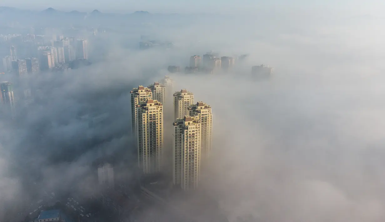 Foto udara ini menunjukkan bangunan yang diselimuti kabut pagi di Bijie, provinsi Guizhou barat daya China (18/11/2021). Bijie  adalah sebuah kota tingkat prefektur di barat laut Provinsi Guizhou, Tiongkok, berbatasan dengan Sichuan di utara dan Yunnan di barat. (AFP/STR)