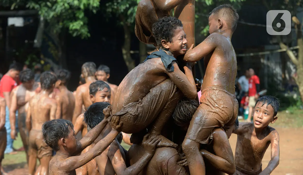 Peserta berusaha menahan temannya untuk menggapai puncak dalam perlombaan panjat pinang di Kampung Bulak, Kelurahan Benda Baru, Pamulang, Tangerang Selatan, Senin (17/8/2020). Lomba di tengah masa pandemi itu guna memeriahkan HUT ke-75 Kemerdekaan RI. (merdeka.com/Dwi Narwoko)