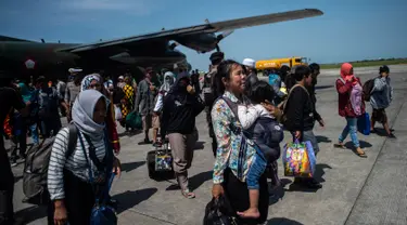 Seorang wanita membawa anaknya ketika mereka tiba di Surabaya, Kamis (4/10). Banyak anak-anak yang terpisah dari keluarganya setelah bencana gempa-tsunami melanda Palu dan Donggala pada 28 September. (AFP Photo/Juni Kriswanto)