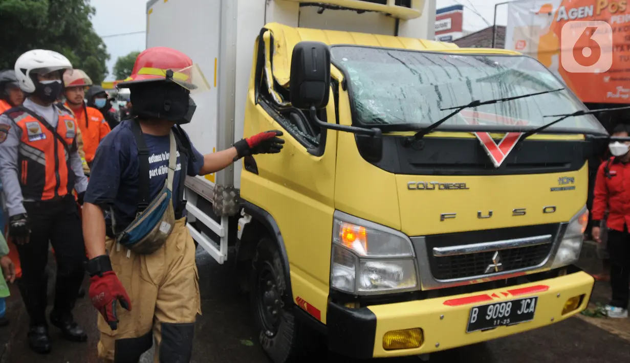 Petugas mengevakuasi truk boks yang rusak parah akibat tertimpa pohon tumbang di Jalan Padjajaran, Kota Tangerang Selatan, Banten, Sabtu (5/3/2022). Pengendara yang terluka karena tertimpa pohon tumbang dibawa ke RSUD Tangerang Selatan. (merdeka.com/Arie Basuki)