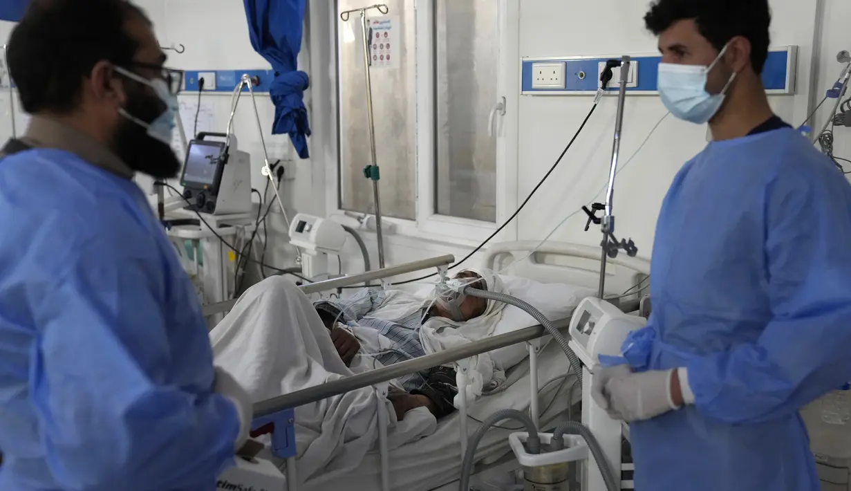 Dua dokter berbicara saat pasien COVID-19 terbaring di tempat tidur di ICU Rumah Sakit Penyakit Menular Afganistan-Jepang di Kabul, 7 Februari 2022. Afghanistan yang hancur secara ekonomi pekan lalu mengalami peningkatan 67 persen dalam jumlah kasus COVID yang dilaporkan. (AP Photo/Hussein Malla)