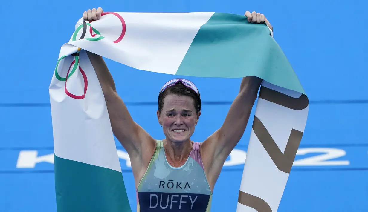 Atlet Bermuda, Flora Duffy berbelebrasi setelah melewati garis finis untuk meraih medali emas dalam triathlon nomor individu putri Olimpiade Tokyo 2020 di Odaiba Marine Park, Selasa (27/7/2021). Flora Duffy menjadi penyumbang medali emas untuk negara berpenduduk 60 ribu orang itu. (AP/David Goldman)