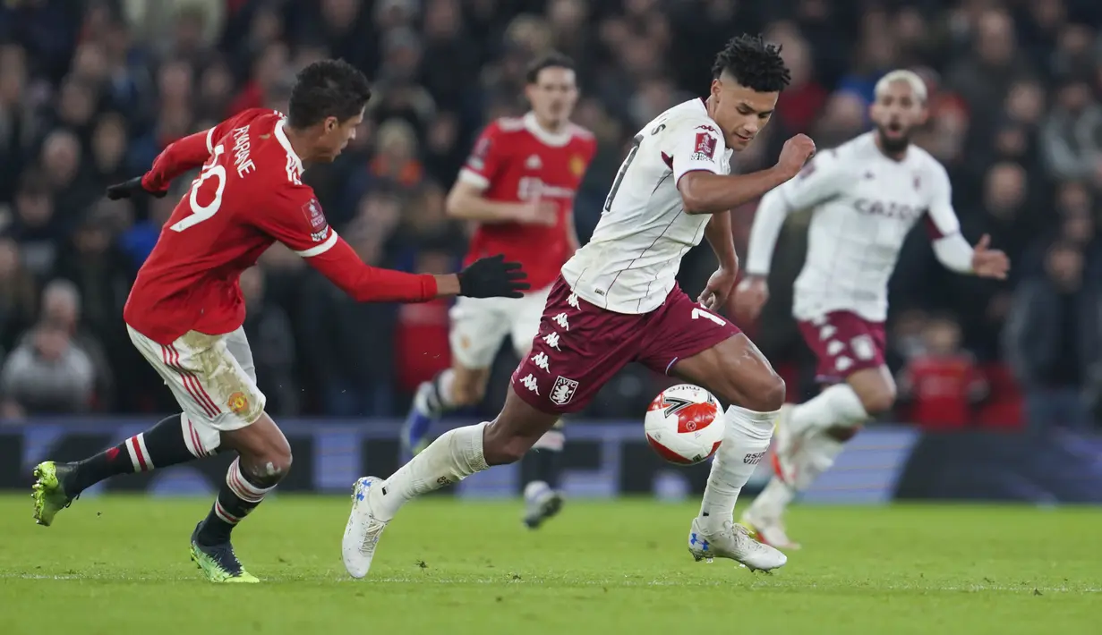 Penyerang Aston Villa,  Ollie Watkins membawa bola dari kejaran bek Manchester United, Raphael Varane pada pertandingan putaran ketiga Piala FA di stadion Old Trafford di Manchester, Inggris, Selasa (11/1/2022). Berkat hasil ini, MU berhak lolos ke putaran keempat dan akan menghadapi Middlesbrough.