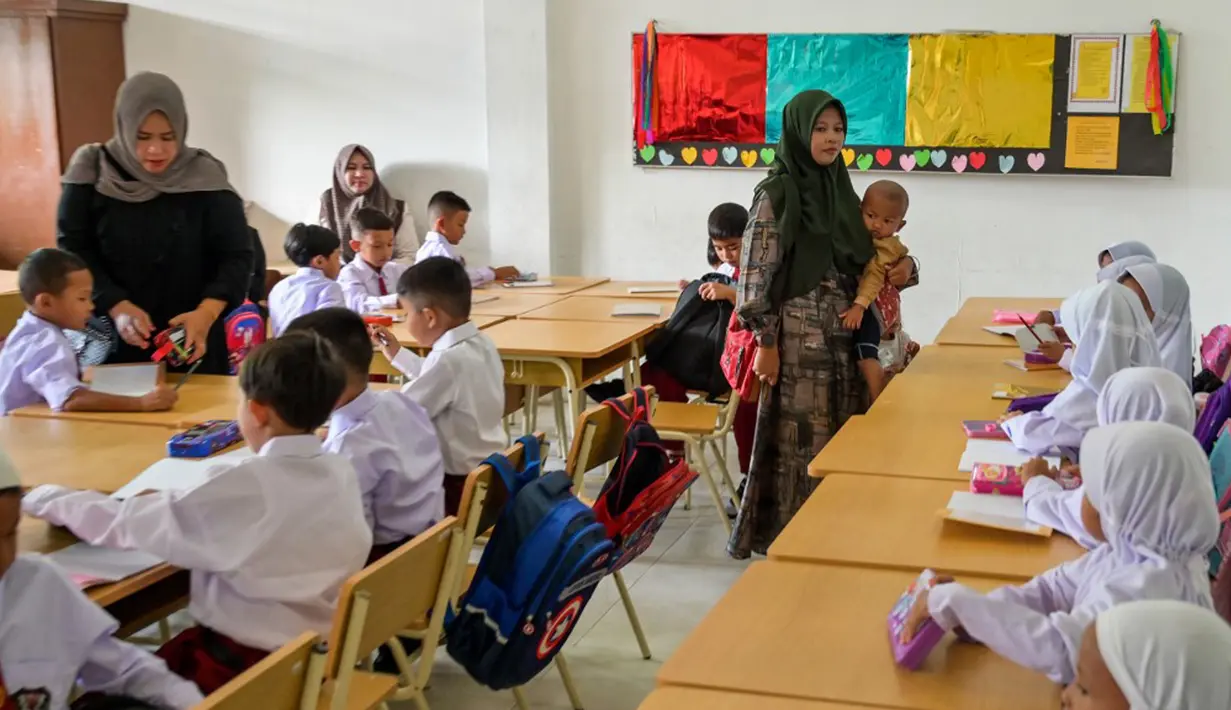 Sejumlah orangtua siswa tampak antusias mendampingi anak mereka mengikuti hari pertama sekolah. (Chaideer MAHYUDDIN/AFP)