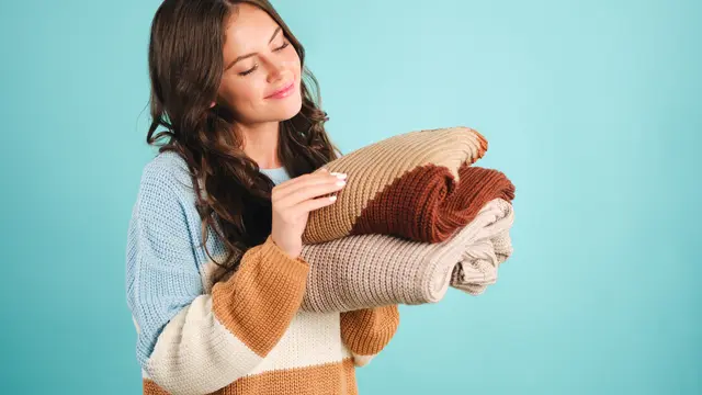 Seorang perempuan sedang memegang setumpuk pakaian berbahan rajut (Foto Dok: Freepik/garetsvisual)