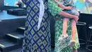 Regina tampil mengenakan daster panjang warna dasar navy, dipadukan syal putih dan sandal. Mikhelia mengenakan mini daster hijau bermotif putih dipadukan aksen belt coklat. [@mikhelia]
