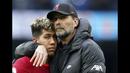Manajer Liverpool, Jurgen Klopp (kanan) memeluk Roberto Firmino pada akhir pertandingan Liga Inggris antara Manchester City dan Liverpool di Etihad Stadium, 10 April 2022. (AP/Jon Super)