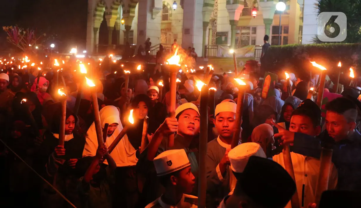 Anak-anak membawa obor sambil berkeliling kampung di kawasan Kota Tangerang, Banten, Jumat (29/7/2022) malam. Pawai obor tersebut digelar untuk menyambut malam pergantian Tahun Baru Islam atau 1 Muharam 1444 H. (Liputan6.com/Angga Yuniar)