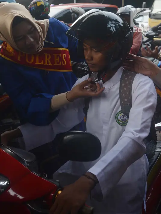 Personel Polisi Wanita (Polwan) Polres Jakarta Timur yang mengenakan busana kebaya, membantu mengenakan helm kepada penggendara motor ketika mengatur arus lalu lintas di Jalan Otista Raya, Jatinegara, Jakarta, Jumat (20/4). (Merdeka.com/Imam Buhori)
