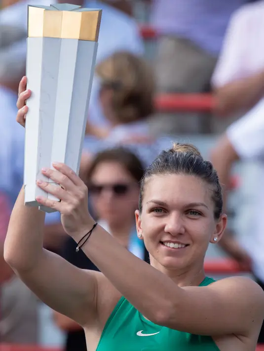 Petenis Rumania, Simona Halep memegang trofi Kanada Terbuka 2018 setelah menaklukkan petenis AS, Sloane Stephens di Montreal, Minggu (12/8). Halep sukses menumbangkan Stephens dengan skor akhir 7-6(6), 3-6, 6-4. (Paul Chiasson/The Canadian Press via AP)