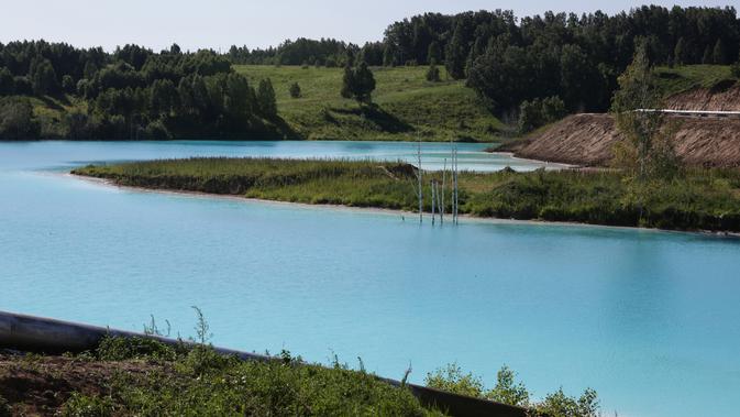 Pemandangan tempat pembuangan abu dari pabrik batubara lokal yang sering disebut 'Maladewa di Siberia' di Danau Novosibirsk, Rusia, Kamis (11/7/2019). Warna biru terang danau itu berasal dari garam kalsium dan oksida logam yang tercampur di dalamnya. (Rostislav NETISOV/AFP)