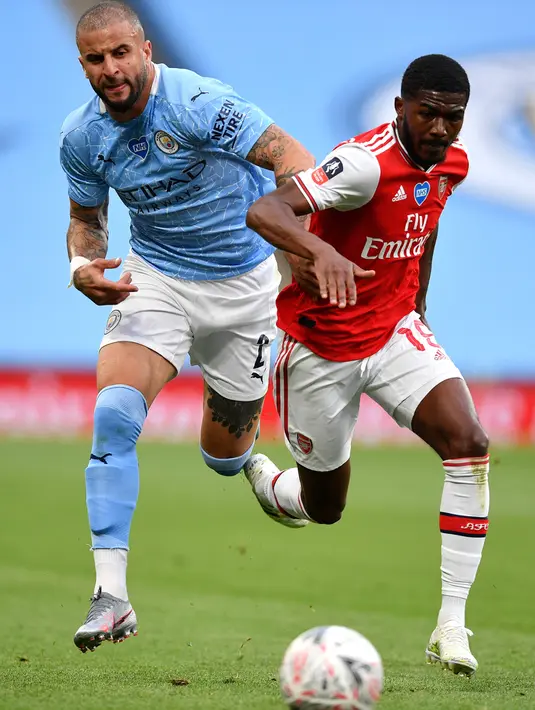 Bek Manchester City, Kyle Walker berebut bola dengan gelandang Arsenal, Ainsley Maitland-Niles selama pertandingan semifinal Piala FA di Wembley di London (18/7/2020). Di final, Arsenal akan menunggu pemenang duel semifinal kedua antara Chelsea melawan MU. (AP Photo/Justin Tallis, Pool)