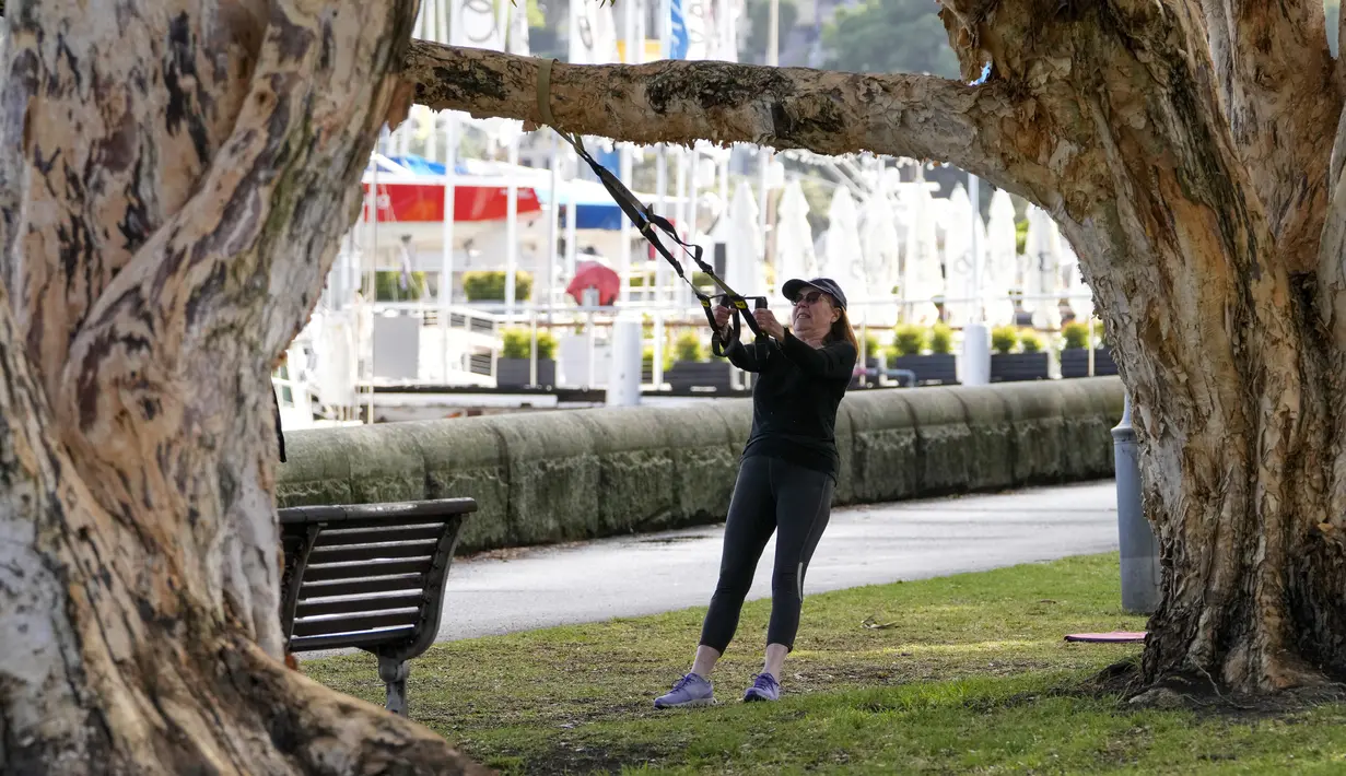 Seorang wanita berolahraga di sebuah taman di pinggiran timur Sydney, pada 14 September 2021. Pelatih kebugaran telah mengubah taman kawasan tepi laut di Rushcutters Bay Sydney menjadi gym luar ruangan untuk menyiasati pembatasan lockdown karena pandemi covid-19. (AP/Mark Baker)