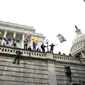 Massa pendukung Presiden Amerika Serikat Donald Trump memanjat dinding barat Capitol Hill, Washington, Amerika Serikat, Rabu (6/1/2021). Seorang pria juga dilaporkan dalam kondisi kritis setelah jatuh dari perancah di Capitol Hill. (AP Photo/Jose Luis Magana)