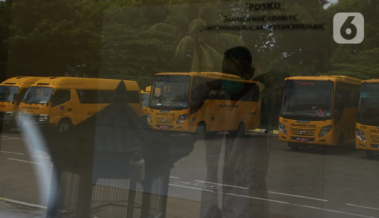 Petugas mengenakan APD sebelum menjemput pasien Covid-19 menggunakan bus sekolah di Puskesmas Jatinegara,  Jakarta, Selasa (22/9/2020). Sejumlah unit bus sekolah kini dialihfungsikan menjadi kendaraan untuk mengantar pasien Covid-19 berstatus OTG menuju Wisma Atlet. (merdeka.com/Imam Buhori)