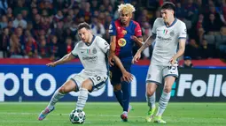 Pemain Barcelona, Lamine Yamal, berusaha melewati pemain Inter Milan Carlos Augusto dan Alessandro Bastoni dalam duel leg pertama semifinal Liga Champions di Estadi Olimpic Lluis Companys, Kamis (1/5/2025) dini hari WIB. (AP Photo/Joan Monfort)