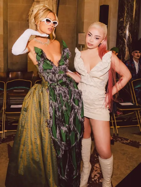 <p>Ice Spice tampil mengenakan mini dress putih bertekstur dengan model kerah v neck siluet sayap. Dipadukan dengan knee boots yang senada dengan dressnya. [@parishilton]</p>