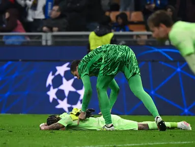 Kiper Barcelona asal Polandia, Wojciech Szczesny menghibur Raphinha setelah pertandingan sepak bola leg kedua semifinal Liga Champions 2024/2025 melawan Inter Milan di Stadion San Siro, Milan, 6 Mei 2025 waktu setempat atau Rabu (7/5/2025) dini hari WIB. (PIERO CRUCIATTI/AFP)