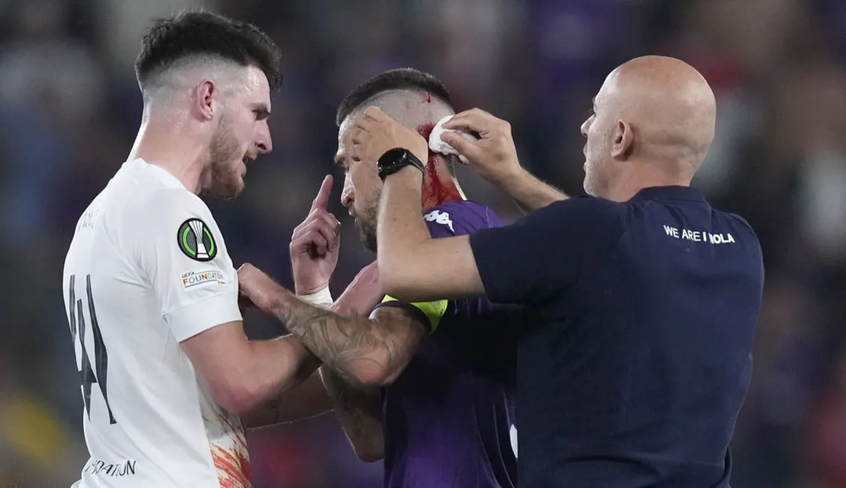 Pemain Fiorentina, Cristiano Biraghi, mendapat perawatan akibat menderita luka di bagian kepala setelah insiden pelemparan benda dari tribun suporter West Ham United pada laga final UEFA Europa Conference League di Stadion Eden Arena, Kamis (8/6/2023). Fiorentina takluk dengan skor 1-2. (AP Photo/Darko Bandic)