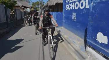 Polisi bersepeda berpatroli di kawasan wisata Pulau Gili Air, Lombok, Nusa Tenggara Barat (NTB), Sabtu (11/8). Patroli dilakukan setelah gempa 7 skala Richter melanda Lombok pada 5 Agustus lalu. (Adek BERRY/AFP)