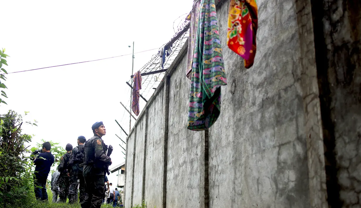 Aparat kepolisian berpatroli di sekitar pagar parimeter penjara menyusul serangan sekelompok pria bersenjata di kota Kidapawan, selatan Filipina, Rabu (4/1). Pelaku menembaki seorang penjaga dan membebaskan 158 dari 1.511 napi. (Ferdinandh CABRERA/AFP)