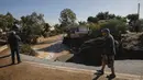Warga memeriksa jalan yang rusak setelah badai di desa Kineta, Athena (25/11/2019). Pihak berwenang di Yunani mengatakan dua orang telah tewas. (AP Photo/Petros Giannakouris)