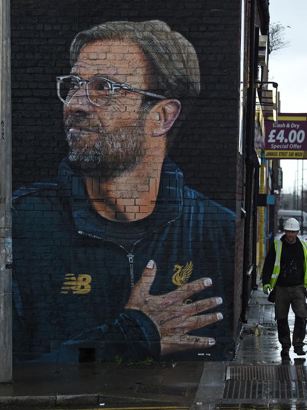 Seorang pekerja melintas dekat mural pelatih klub Liverpool, Jurgen Klopp di Jamaica Street, pusat kota Baltic Triangle di Liverpool, Senin (10/12). Pengerjaan mural itu dimulai sejak 8 November 2018 lalu oleh seniman jalanan 