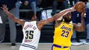 Pebasket Los Angeles Lakers, LeBron James, berusaha melewati hadangan pemain Denver Nuggets, PJ Dozier, pada laga NBA di The Arena, Senin (11/8/2020). LA Lakers menang dengan skor 124-121. (AP Photo/Ashley Landis, Pool)