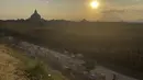 Seorang wanita berjalan dengan sapi dalam perjalanan pulang di Bagan, distrik Nyaung U, Myanmar tengah, Rabu (8/12/2021). Bagan merupakan merupakan pusat konsentrasi kuil, pagoda dan stupa Budha terbesar di dunia pada sekitar abad 11 dan 12. (AP Photo)