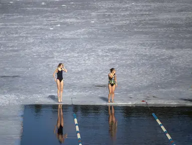 Para perenang bersiap bertanding dalam kompetisi renang musim dingin di lubang es sepanjang 25 meter di danau dekat Vilnius, Lithuania, Sabtu (6/3/2021).  Suhu air saat itu 3 derajat Celcius, sedangkan udaranya -3 derajat Celsius. (AP Photo/Mindaugas Kulbis)