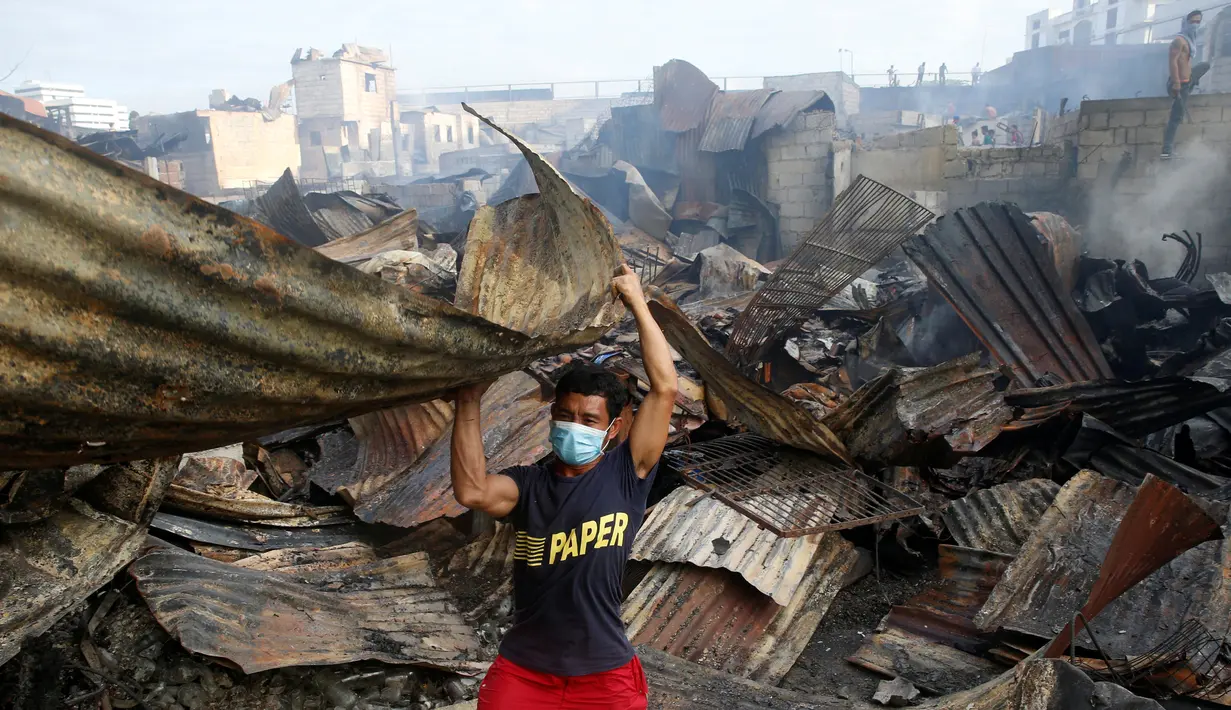 Seorang warga mengangkat puing-puing bangunan usai kebakaran kota Quezon, Metro Manila di Filipina (28/12). Dalam kejadian ini sejumlah warga mengalami luka-luka dan tidak ada korban jiwa. (REUTERS/Erik De Castro)