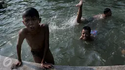 Anak-anak  berenang di kolam air mancur di kawasan Jalan Diponogoro, Jakarta, Jumat (31/7/2015). Minimnya lahan bermain di Ibukota, membuat mereka memanfaatkan kolam air mancur sebagai tempat berenang. (Liputan6/Johan Tallo)