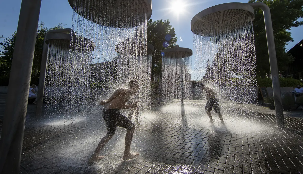 Anak-anak mendinginkan diri di air mancur umum di Vilnius, Lithuania, 26 Juni 2022. Gelombang panas berlanjut di Lithuania saat suhu naik hingga 32 derajat Celcius (89,6 derajat Fahrenheit). (AP Photo/Mindaugas Kulbis)