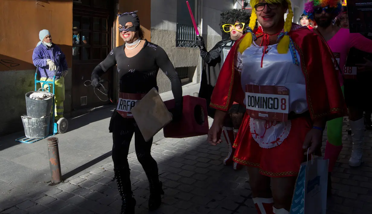 Seorang pekerja melihat peserta yang mengenakan kostum dan sepatu hak tinggi sebelum memulai balapan high heels pria di Madrid, Spanyol (18/1). Acara ini digelar untuk mempromosikan karnaval di Puerto de la Cruz. (AP Photo / Paul White)