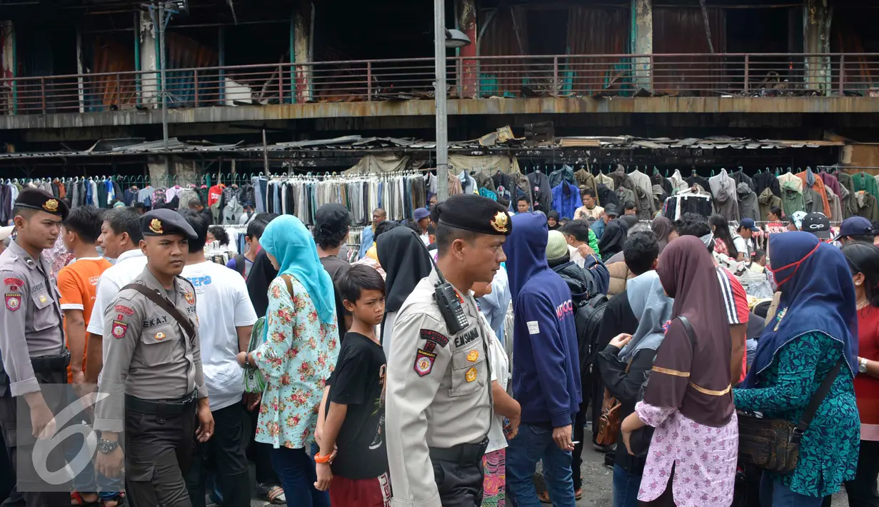 Petugas kepolisian berjaga di sekitar tempat perdagangan di depan gedung Pasar Senen pasca kebakaran, Jakarta, Minggu (22/1). (Liputan6.com/Helmi Affandi)