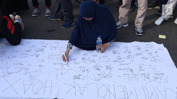 Warga menandatangani spanduk dukungan anti hoax di kawasan Bundaran Hotel Indonesia, Jakarta, Minggu (18/11). PB HMI mensosialisasikan Hoax sebagai ancaman demokrasi di Indonesia. (Liputan6.com/Helmi Fithriansyah)