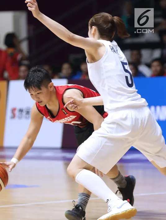 Pebasket putri Indonesia, Nathania Claresta Orville (kiri) mencoba menembus adangan pemain Korea, Park Hyejin pada babak penyisihan Grup X Basket Putri Asian Games 2018 di Jakarta, Rabu (15/8). Indonesia kalah 40-108. (Liputan6.com/Helmi Fithriansyah)