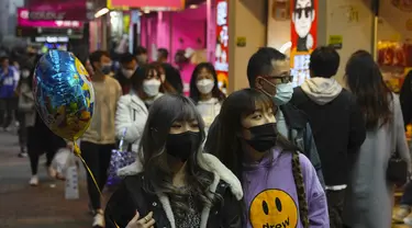 Orang-orang memakai masker untuk melindungi diri dari penyebaran virus corona, berjalan di jalan di Hong Kong (14/1/2022). Hong Kong akan menangguhkan penerbangan transit dari sekitar 150 negara dan wilayah yang dianggap berisiko tinggi karena virus corona selama sebulan penuh. (AP Photo/Kin Cheung)