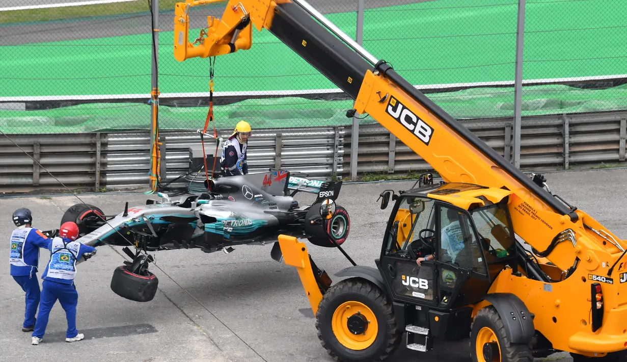 Petugas mengangkat mobil Lewis Hamilton usai menabrak dinding pembatas lintasan saat kualifikasi F1 GP Brasil di sirkuit Interlagos di Sao Paulo, Brasil (11/11). (AFP Photo/Nelson Almeida)