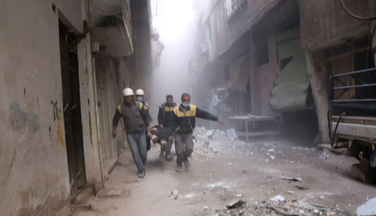 Anggota Syrian Civil Defense yang dikenal dengan White Helmets membawa korban luka dalam serangan udara pemerintah Suriah di Ghouta, pinggiran kota Damaskus, Suriah, Jumat (23/2). (Syrian Civil Defense White Helmets via AP)
