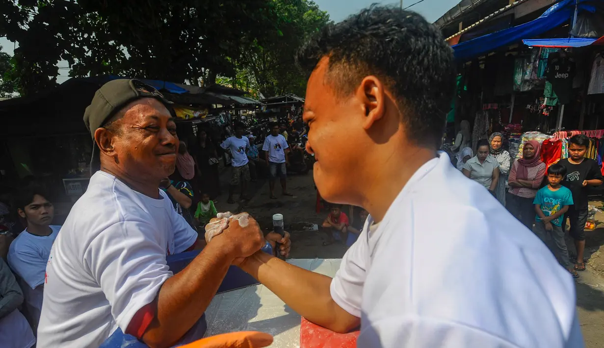 Pedagang pasar saat mengikuti lomba panco antar pedagang dan pengunjung pasar di Pasar Rakyat Ciseeng, Bogor, Sabtu (20/7/2024). (merdeka.com/Arie Basuki)