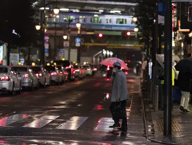 Seorang pria melintasi persimpangan menuju stasiun kereta api di Tokyo, Jumat (5/3/2021).  PM Jepang Yoshihide Suga mengumumkan bahwa pemerintahnya memperpanjang keadaan darurat di wilayah Tokyo selama dua minggu lagi untuk mencegah terjadinya lonjakan infeksi COVID-19. (AP Photo/Hiro Komae)